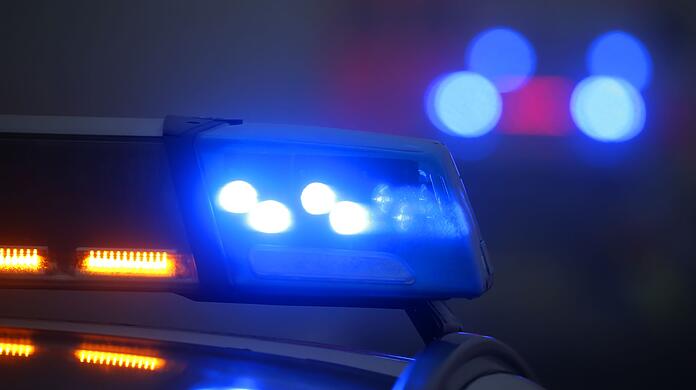 Ein Polizeiauto mit eingeschaltetem Blaulicht steht an einer Unfallstelle.