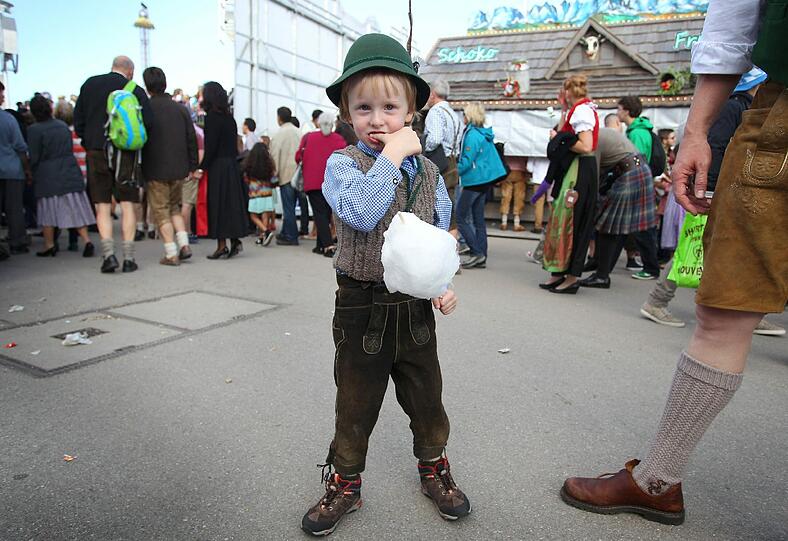 Früh übt sich: Ein junger Wiesn-Gast verköstigt eine Zuckerwatte - natürlich in traditioneller Tracht.