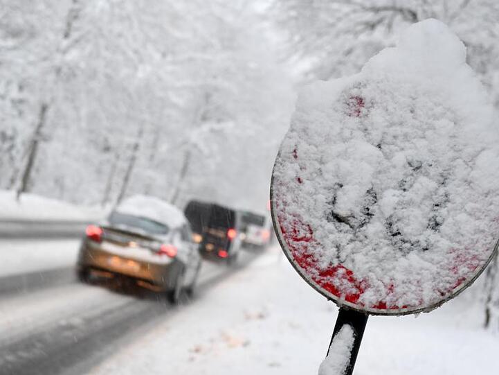 Autos fahren auf einer verschneiten Straße in Berchtesgaden (Bayern). Foto: Tobias Hase/Archiv