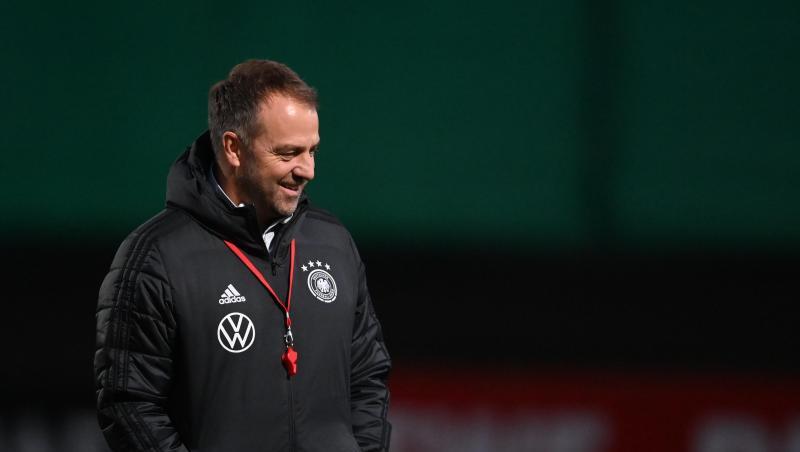 Der Mann mit der roten Trillerpfeife: Bundestrainer Hansi Flick steht lächelnd auf dem Platz.