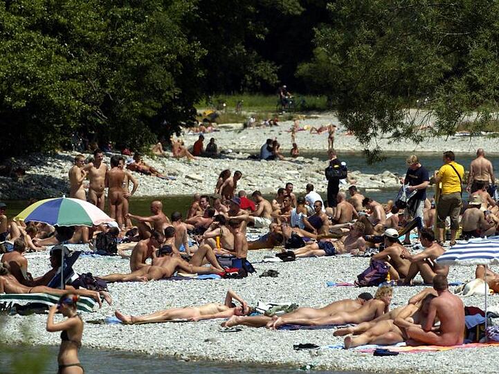 Zahlreiche Menschen liegen bei strahlendem Sonnenschein entlang der Isar in München. (Archivbild)