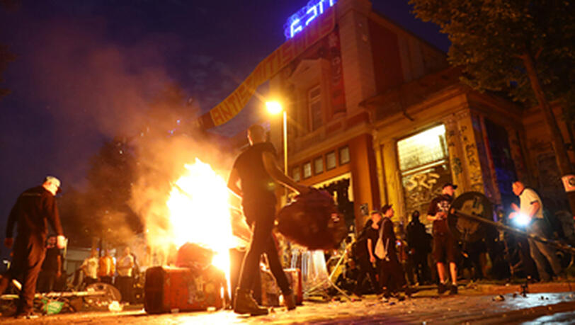 Aktivisten stehenvor der Roten Flora um eine brennende Barrikade. Knapp sechs Monate nach den schweren Ausschreitungen beim G20-Gipfel beginnen die Ermittlungen gegen einen Münchner Polizisten, der offenbar bei den Krawallen mitgewirkt haben soll. Aktivisten stehenvor der Roten Flora um eine brennende Barrikade. Knapp sechs Monate nach den schweren Ausschreitungen beim G20-Gipfel beginnen die Ermittlungen gegen einen Münchner Polizisten, der offenbar bei den Krawallen mitgewirkt haben soll.