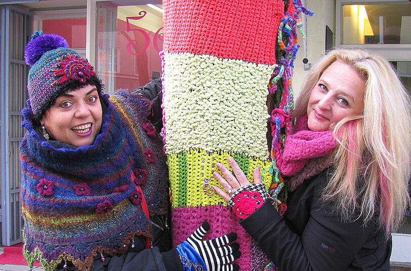 Petra Perle (l.) und Uta Alexander haben einen Baum vor dem Laden &bdquo;5ever&ldquo; in der Buttermelcherstraße mit Wolle eingekleidet.
