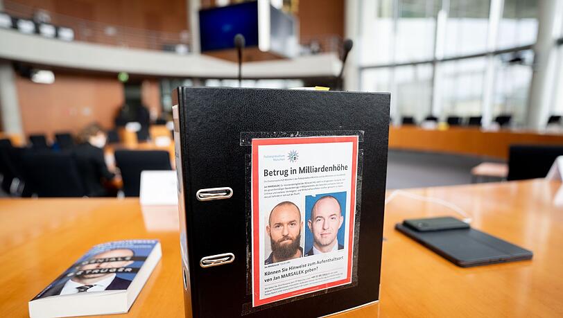 Ein Aktenordner mit Fahndungsfotos von Jan Marsalek im Untersuchungsausschuss des Bundestags. Ist der frühere Wirecard-Vorstand in Russland?