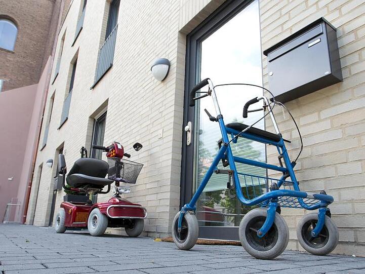 Ein Rollator und ein Elektromobil stehen vor einer Seniorenwohnung.