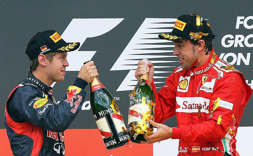 Sebastian Vettel und Fernando Alonso prosten sich mit Champagnerflaschen zu.