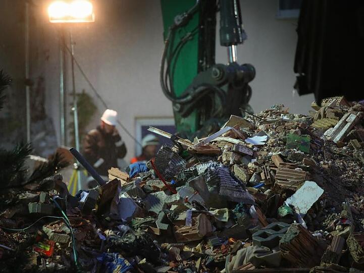 Bagger tragen Trümmer des explodierten Wohnhauses ab.