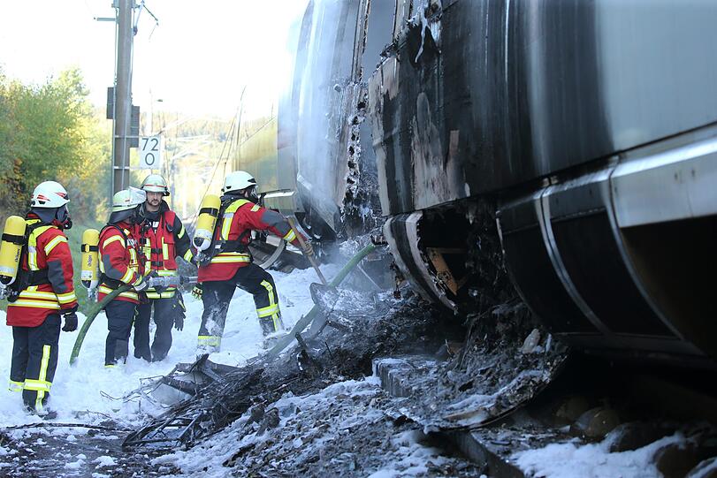 Feuerwehrleute löschen den brennenden ICE-Wagen, der auf der Schnellstrecke zwischen Frankfurt und Köln Feuer gefangen hatte.