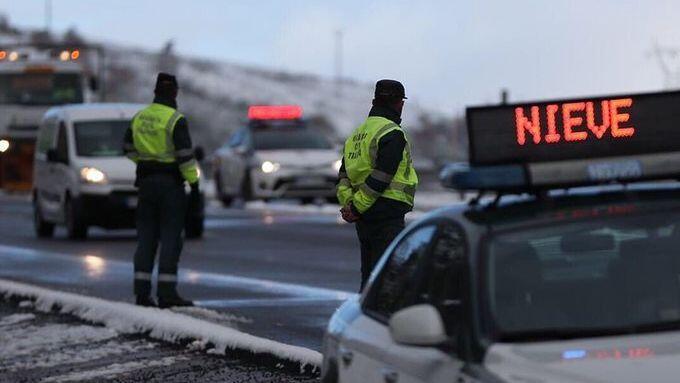 Zwei Beamte der Zivilgarde überwachen den Einsatz von Schneeketten in einem verschneiten Gebiet.