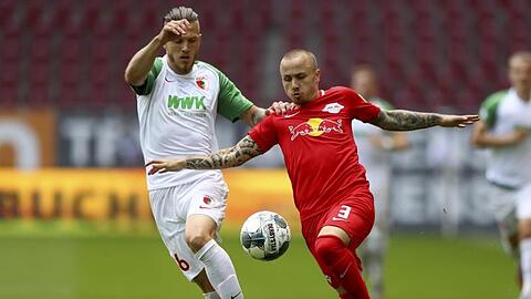 Der Augsburger Jeffrey Gouweleeuw und der Leipziger Angelino (l-r.) im Duell um den Ball. Foto: Matthias Schrader/AP/POOL/dpa