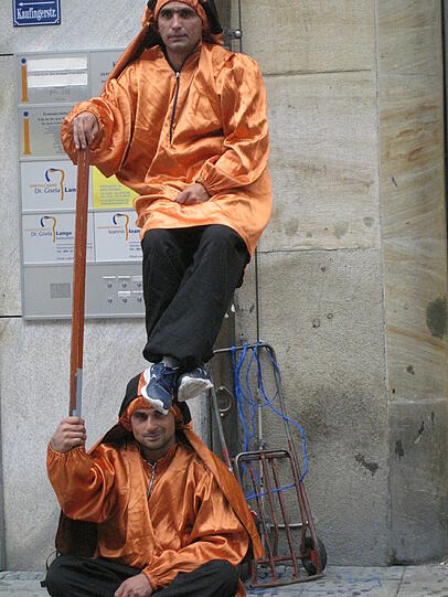 ... ist eine Stange. Der Mann sitzt auf einer Platte, die nach oben und durch den Ärmel nach vorne führt. Dazu gehört der Stock, und dieser wird...
