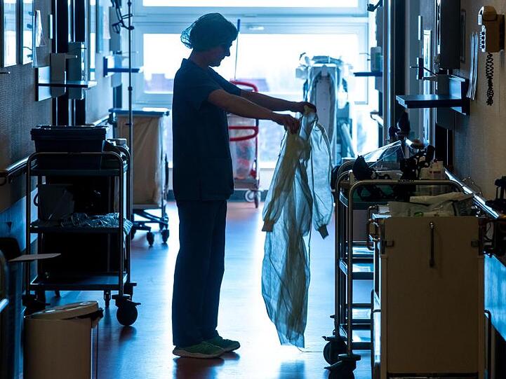 Eine Krankenschwester legt auf einer Corona-Isolierstation Schutzkleidung an.