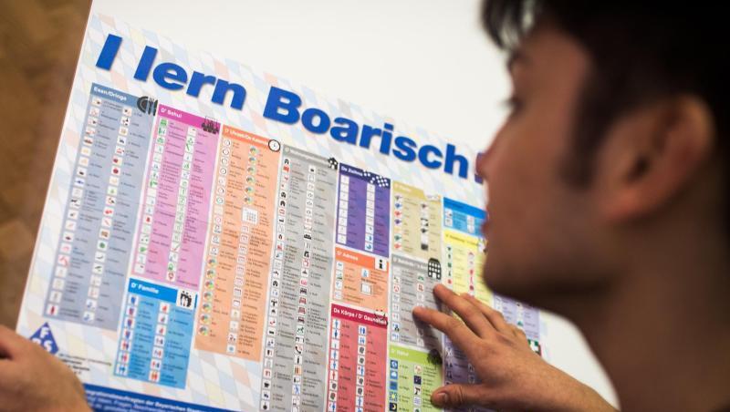 Ein Mann liest die Sprachtafel "I lern Boarisch". Foto: Alexander Heinl/dpa/Archivbild Ein Mann liest die Sprachtafel "I lern Boarisch". Foto: Alexander Heinl/dpa/Archivbild