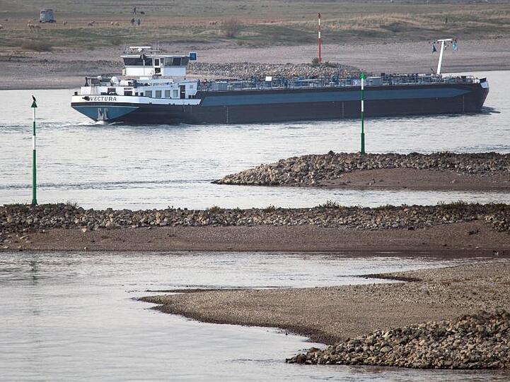 Ein Tankschiff fährt bei Niedrigwasser zwischen trocken gefallenden Buhnen auf dem Rhein.
