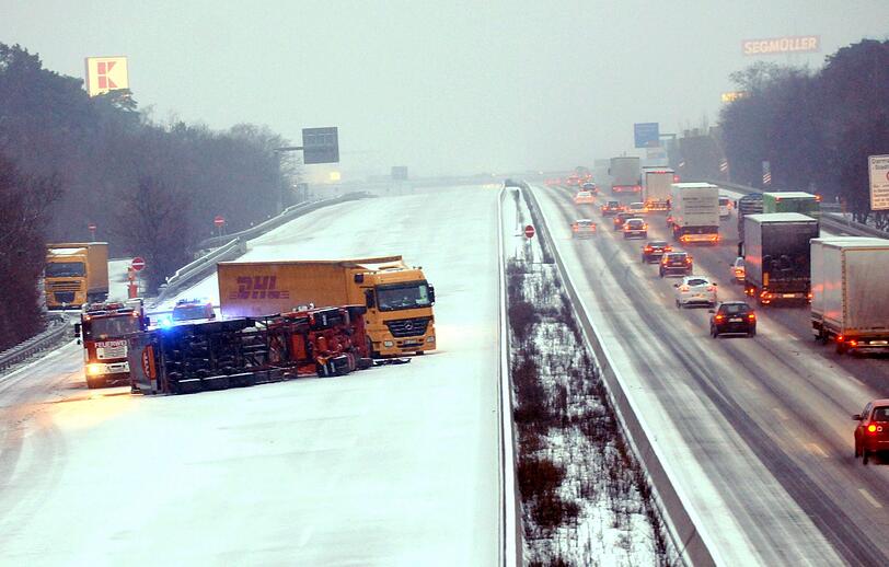 Auf der A5 bei Weiterstadt in Hessen liegen zwei Lkw auf der schneeglatten Fahrbahn.
