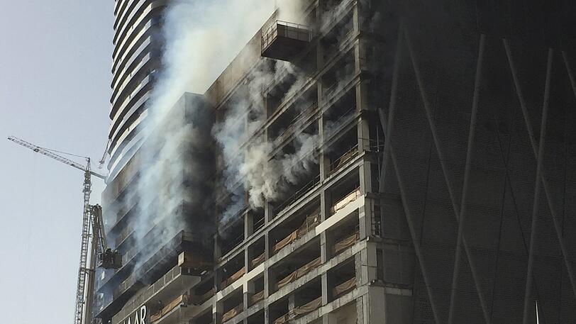 Dichte Rauchschwaden steigen in Dubai aus einem im Bau befindlichen Hochhaus auf. Riesige schwarze Rauchwolken sind über die Stadt zu sehen.