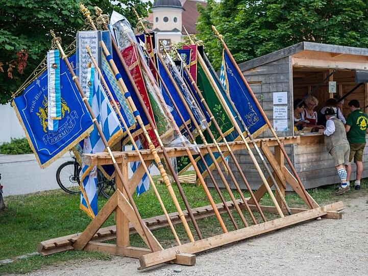 Ein Fahnenhalter mit vielen Vereinsfahnen steht neben einer Bude. Foto: Lino Mirgeler