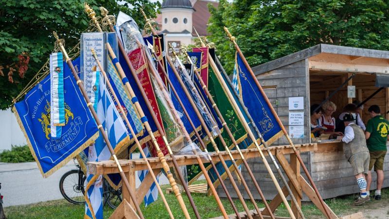 Ein Fahnenhalter mit vielen Vereinsfahnen steht neben einer Bude. Foto: Lino Mirgeler Ein Fahnenhalter mit vielen Vereinsfahnen steht neben einer Bude. Foto: Lino Mirgeler
