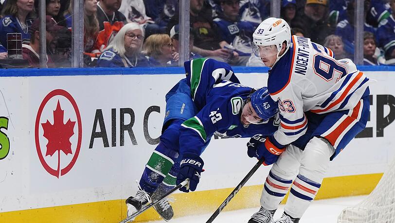 Quinn Hughes von den Vancouver Canucks wird von Ryan Nugent-Hopkins von den Edmonton Oilers zu Fall gebracht.