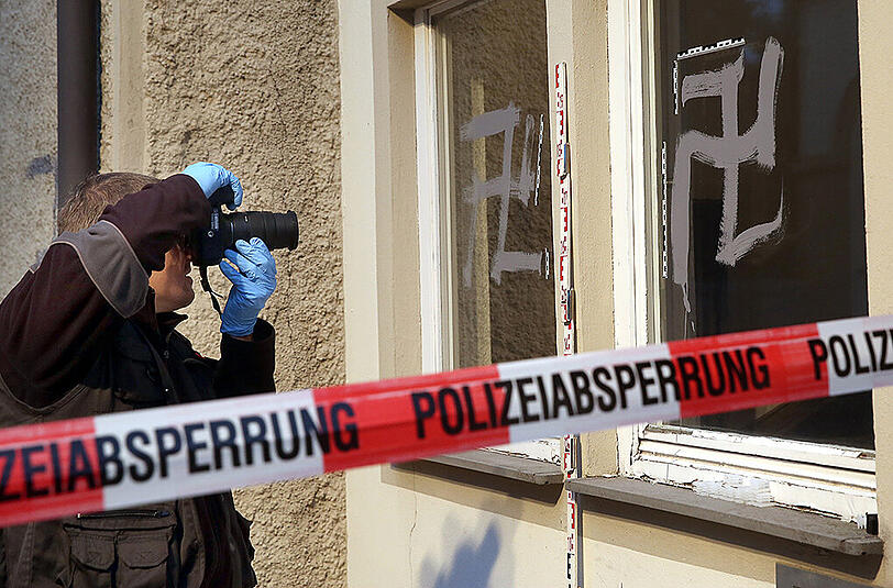 Ein Mitarbeiter der Spurensicherung der Polizei fotografiert am 19.09.2015 vor einer Notunterkunft für Flüchtlinge in Riedlingen (Baden-Württemberg) Schmierereien und Hetzparolen, darunter auch Hakenkreuze.