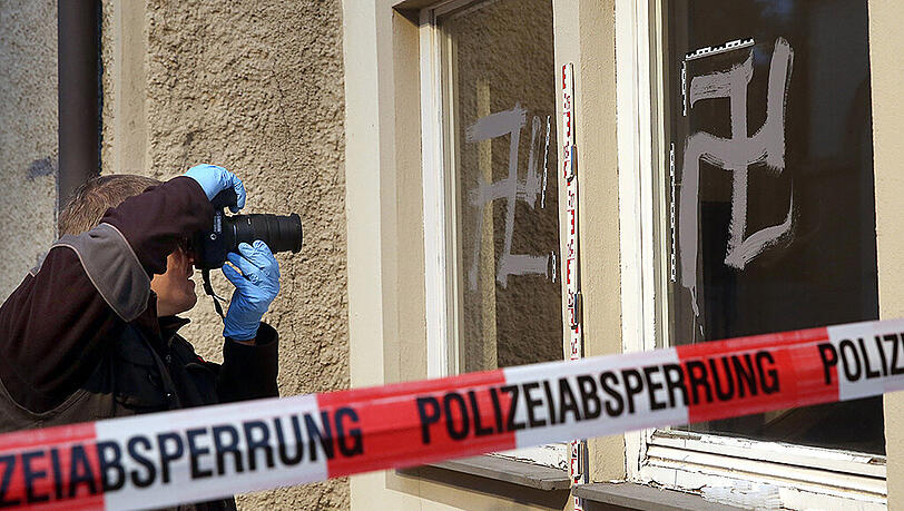 Ein Mitarbeiter der Spurensicherung der Polizei fotografiert am 19.09.2015 vor einer Notunterkunft für Flüchtlinge in Riedlingen (Baden-Württemberg) Schmierereien und Hetzparolen, darunter auch Hakenkreuze. Ein Mitarbeiter der Spurensicherung der Polizei fotografiert am 19.09.2015 vor einer Notunterkunft für Flüchtlinge in Riedlingen (Baden-Württemberg) Schmierereien und Hetzparolen, darunter auch Hakenkreuze.
