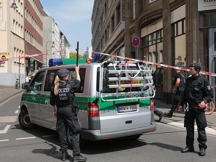 Ein Polizeiauto fährt unter der Absperrung durch.