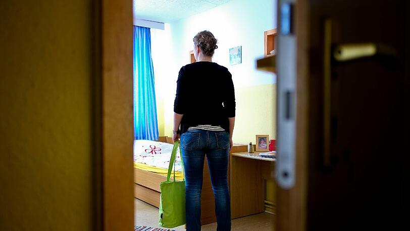 Eine junge Frau steht in ihrem Zimmer in einem Frauenhaus. Wie lange sie hier bleiben muss, ist noch offen. Eine junge Frau steht in ihrem Zimmer in einem Frauenhaus. Wie lange sie hier bleiben muss, ist noch offen.