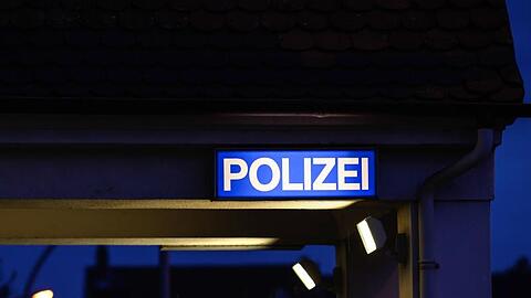 Ein Schild mit der Aufschrift "Polizei" leuchtet am Eingangsbereich der Polizeistation. Foto: Silas Stein/dpa/Symbolbild
