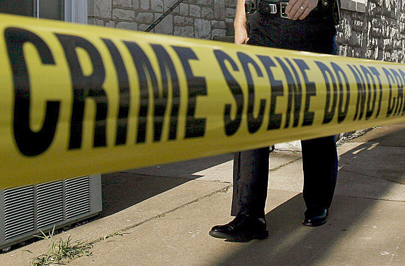 Ein US-Polizist sichert mit einem Absperrband einen Tatort. Foto: Larry W. Smith/Illustration