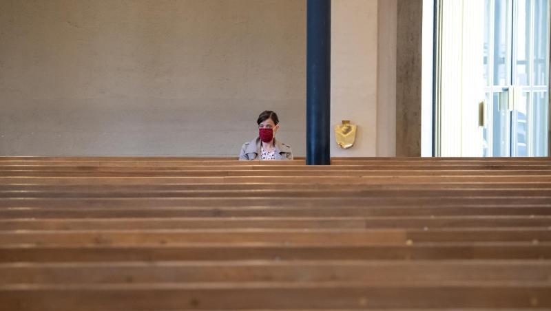 Eine Frau mit Mundschutz verfolgt einen Gottesdienst in einer Kirche. Foto: Sven Hoppe/dpa/Archivbild