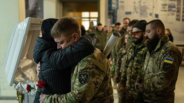 Die Mutter der getöteten ukrainischen Soldatin des Khartia-Bataillons Vladyslava Chernyh umarmt einen Kameraden ihrer Tochter während einer Beerdigungszeremonie.
