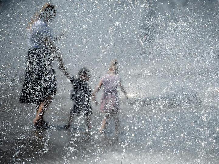 Eine Frau und zwei Kinder kühlen sich am Stachus in einem Brunnen ab. Foto: Sven Hoppe/dpa/Archivbild