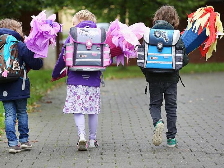 Drei Erstklässler sind mit ihren Schultüten auf dem Weg zur Einschulung in die 1. Klasse. Foto: Thomas Warnack/Archiv