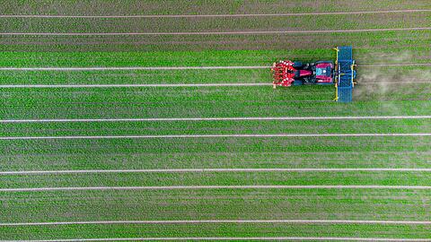 Ein Landwirt fährt mit seinem Trecker über ein Feld.