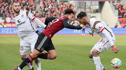 Jens Castrop (M) kämpft mit Marcel Hartel (l) und Leart Paqarada von St. Pauli um den Ball.