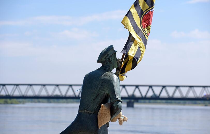 Hilfskräfte haben am 09.06.2013 in Lauenburg (Schleswig-Holstein) der Skulptur "Der Rufer" , die nahe der Elbbrücke steht, einen Sandsack und eine Stadtfahne angesteckt.