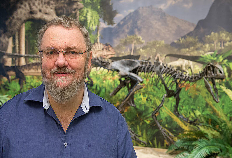 Museumsleiter Joachim Rabold posiert neben dem Dino-Skelett.