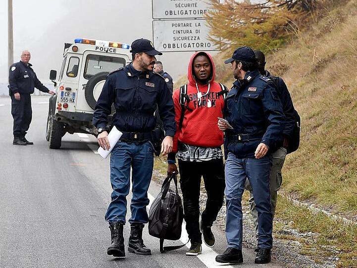 Italienische Polizisten überprüfen einen Mann nahe der Grenze zu Frankreich.