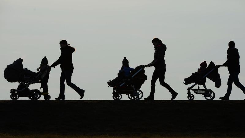 Drei Mütter schieben ihre Kinderwagen eine Landstraße entlang. Ab diesem Montag erhalten die Eltern von rund 18 Millionen Kindern in Deutschland 300 Euro extra.