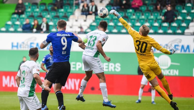 Fürths Torwart Sascha Burchert (r), Marco Caligiuri (2.v.r.) und Maximilian Wittek (l) kämpfen mit Bielefelds Fabian Klos (2.v.l.) um den Ball. Foto: Nicolas Armer/dpa