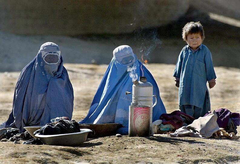 Das Bild aus dem Jahr 2002 zeigt zwei Frauen und einen Jungen, die in Kabul Wasser kochen.
