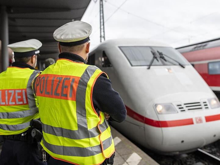 Zwei Beamte der Bundespolizei beobachten einen ICE. Foto: Patrick Seeger/dpa