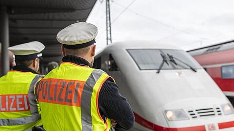 Zwei Beamte der Bundespolizei beobachten einen ICE. Foto: Patrick Seeger/dpa