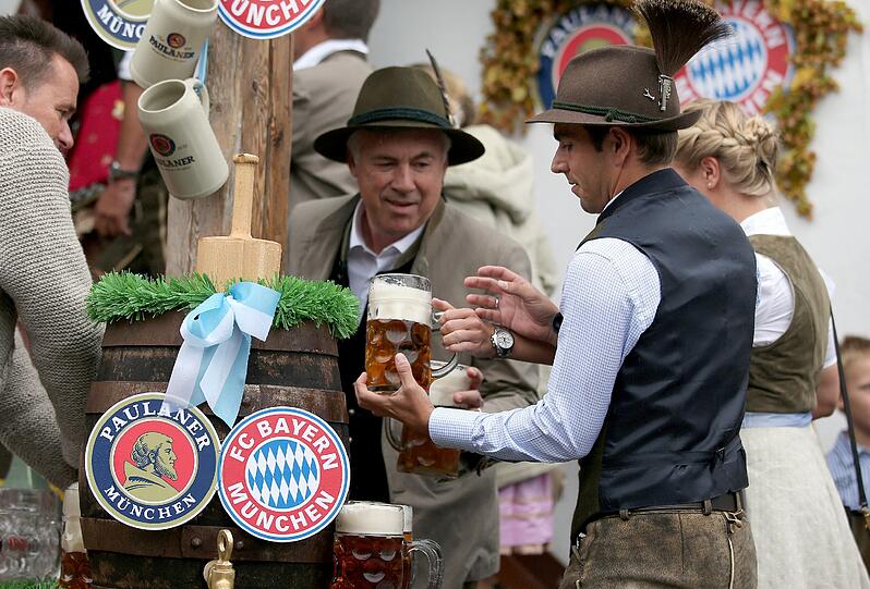 Der Tabellenführer zapft o': FCB-Coach Carlo Ancelotti und Philipp Lahm behalten das Bierfass im Auge.