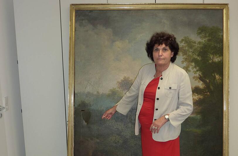 Ingrid Heckner vor dem beschädigten Gemälde "Die waldige Hügellandschaft" von Ferdinand Kobell.