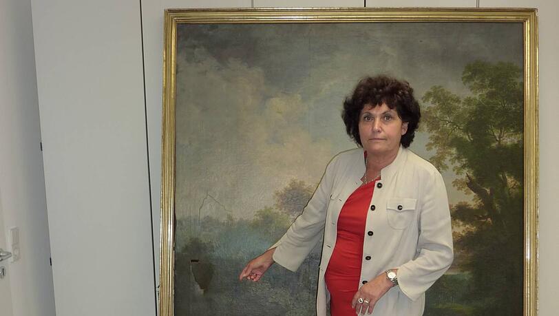 Ingrid Heckner vor dem beschädigten Gemälde "Die waldige Hügellandschaft" von Ferdinand Kobell. Ingrid Heckner vor dem beschädigten Gemälde "Die waldige Hügellandschaft" von Ferdinand Kobell.