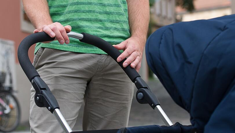 Ein junger Vater mit einem Kinderwagen (Symbolbild).
