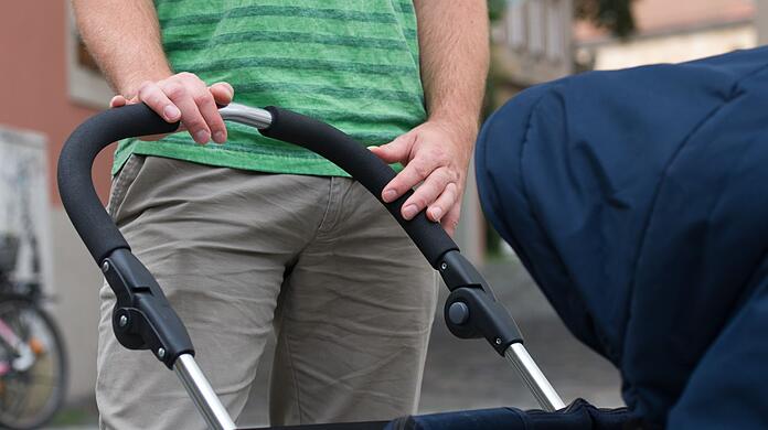 Ein junger Vater mit einem Kinderwagen (Symbolbild).