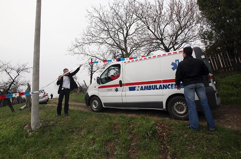 Ein Krankenwagen fährt in das abgeriegelte Dorf Velika Ivanca, wo der Täter 13 Verwandte erschossen und seine Frau und sich selbst schwer verletzt hat.