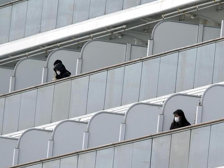 Passagiere mit Mundschutz auf Balkonen des Kreuzfahrtschiffs "Diamond Princess" im Hafen von Yokohama.